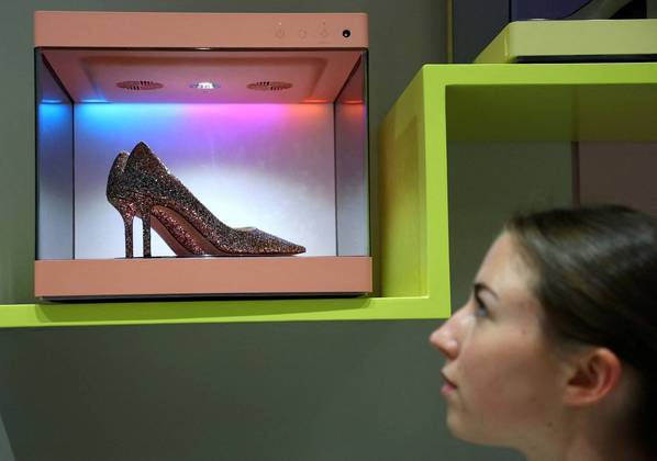Uma modelo olha com uma quantidade razoável de estranhamento para a novíssima LG Styler ShoeCare, uma caixa que exibe e conserva sapatos e sneakers. O gadget protege calçados caríssimos de umidade e cheiros ruins. O aparelho foi exibido na feira de tecnologia IFA, na Alemanha