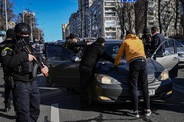 Policiais ucranianos revistam homem suspeito