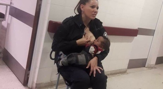 Policial, ainda fardada, amamentando um bebê em hospital