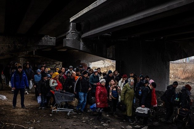 Popula&ccedil;&atilde;o evacuada fica sob uma ponte destru&iacute;da enquanto fogem da cidade de Irpin, a noroeste de Kiev