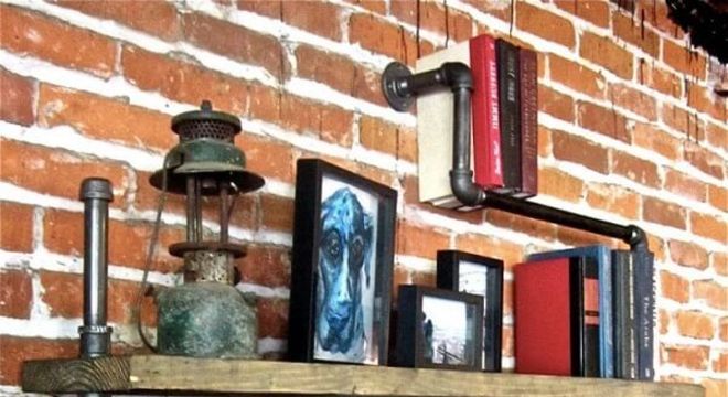 Prateleira para livros formada com estrutura de madeira e canos