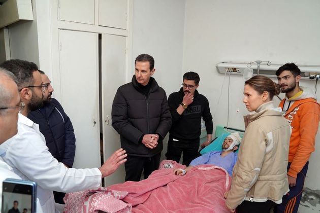 Bashar al-Assad (ao centro, com jaqueta de zíper), presidente sírio, visita um sobrevivente do terremoto no Tishreen University Hospital, na cidade de Latakia. A primeira-dama, Asma al-Assad (à direita), também estava presente