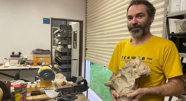 Professor Rodrigo Santucci mostra o fóssil da vértebra de um saurópode brasileiro