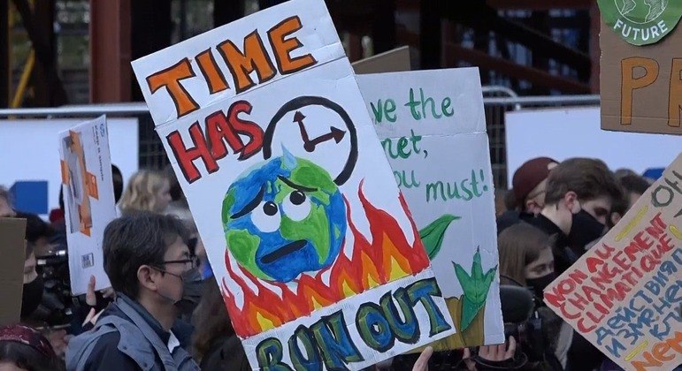 Um homem segurando um cartaz com o dizer: "Time has run out" ("O tempo se esgotou")
