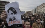 Grupo leva cartazes às ruas em manifestação contra a invasão russa. O presidente russo é criticado por meio de uma caricatura que lembra Adolf Hitler, líder da Alemanha nazista na Segunda Guerra Mundial