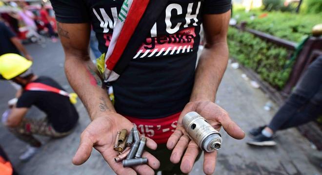 Manifestante mostra cartuchos de balas disparadas pela polícia do Iraque