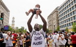 Um manifestante com camiseta Black Lives Matter levanta um bebê durante as manifestações de sábado (6) em Washington
