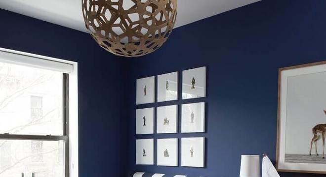 quarto azul marinho com quadros decorativos e cabeceira estofada listrada 