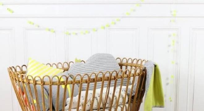 Quarto de bebê com berço de vime e almofadas decorativas