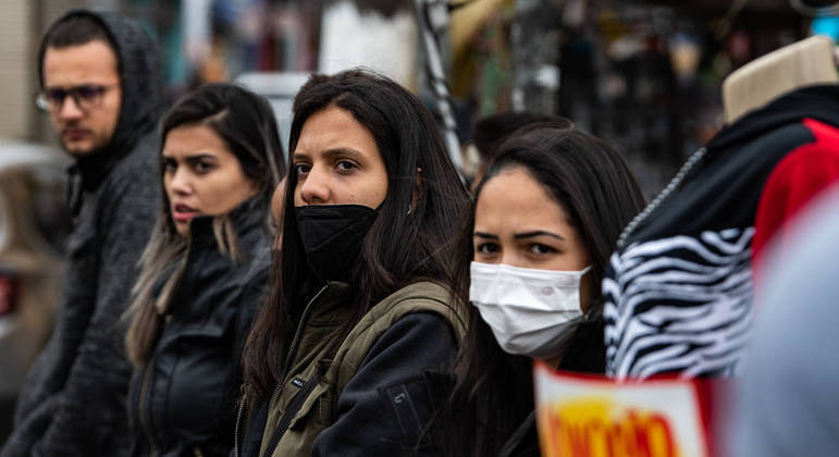 Pessoas na rua usando máscara, em São Paulo