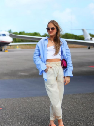 Ainda em Trancoso, ela usou um aerolook composto de camisa azul, croppe branco de manga única e calça nude de cintura alta. Bolsa cor-de-rosa transversal, chinelo e óculos de sol arremataram o visual