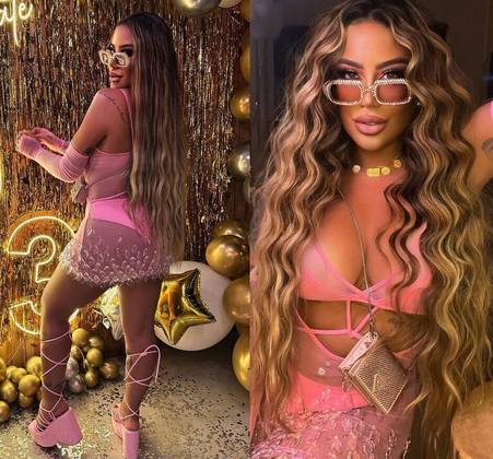 Para a virada de ano, a influenciadora escolheu um look todo rosa, seguindo a tendência Barbiecore com ousadia. Ela começou 2023 com um vestido rosa transparente e recortado, cheio de pedrarias na barra. Por baixo da peça, usou um biquíni rosa de cintura alta. E complementou o visual com luvas longas, sandálias plataforma com amarrações e óculos brilhante