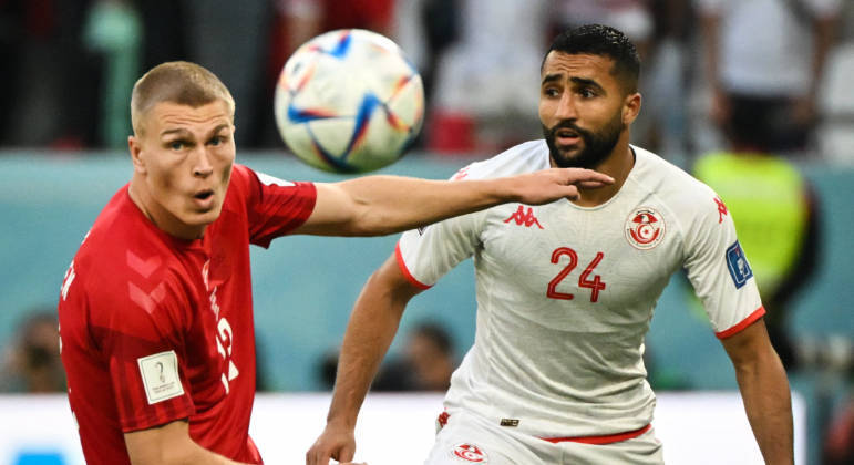 Rasmus Kristensen (esq), da Dinamarca, e Ali Abdi, da Tunísia, disputam a bola no Catar