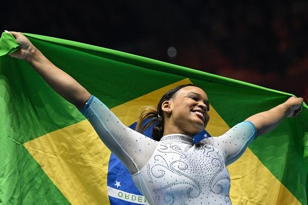 A campeã brasileira Rebeca Andrade comemora com a bandeira do Brasil após vencer a final do individual geral feminino no Mundial de Ginástica em Liverpool, norte da Inglaterra, em 3 de novembro