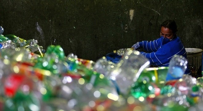 Mulher trabalha na separação do lixo reciclável em uma cooperativa