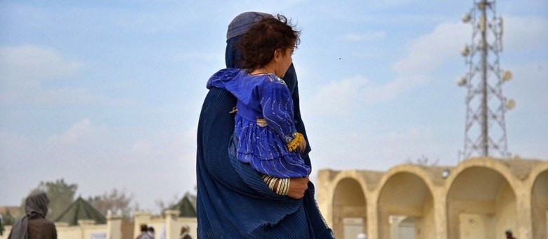 Refugiada afegã carrega criança em um centro de registro perto da fronteira Afeganistão-Paquistão (Sanuallah Seiam/AFP - 06.11.2023)