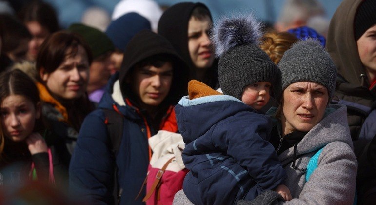 Refugiados fazem fila para entrar em um ônibus que irá os levar para fora da Ucrânia