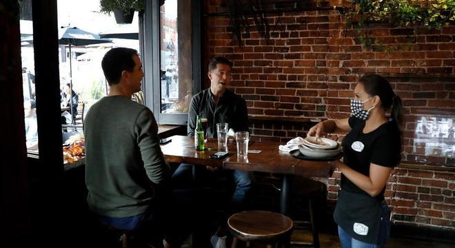 Garçonete usa máscara enquanto atende clientes em restaurante de NY