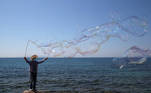 A man waring a protective face mask makes soap bubbles following the easing of measures against the spread of the coronavirus disease (COVID-19) in Faliro suburb, near Athens, Greece, April 3, 2021. REUTERS/Costas Baltas