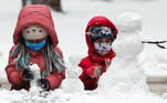 Children wearing protective face masks amid the coronavirus disease (COVID-19) outbreak make a snowman in a snow-covered park after snowfall in Kyiv, Ukraine January 28, 2021. REUTERS/Gleb Garanich