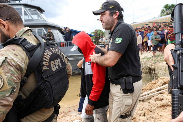 O suspeito estava encapuzado e com o rosto coberto quando foi escoltado até a embarcação, nesta quarta-feira (15)