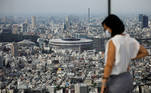 The National Stadium, the main stadium of Tokyo 2020 Olympics and Paralympics, is seen past a visitor wearing a protective face mask amid the coronavirus disease (COVID-19) at an observation deck in Tokyo, Japan July 20, 2020. REUTERS/Issei Kato/File Photo TPX IMAGES OF THE DAY SEARCH 'POY SPORTS' FOR THIS STORY. SEARCH 'REUTERS POY' FOR ALL BEST OF 2020 PACKAGES
