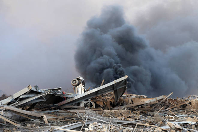 Um carro sob escombros dos prédios destruídos do porto após a explosão