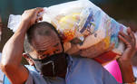 A man carries a plastic bag with food aid distributed by the "G10 das Favelas", a group of slum's entrepreneurs, amid the coronavirus disease (COVID-19) pandemic at Heliopolis slum in Sao Paulo, Brazil April 14, 2021. REUTERS/Carla Carniel