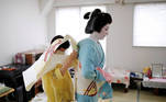 A kimono dresser helps Koiku, who is a geisha, put on her kimono as Koiku gets ready at Ikuko's home to work at a party being hosted by customers at a restaurant, where she will be entertaining with other geisha, during the coronavirus disease (COVID-19) outbreak, in Tokyo, Japan, June 23, 2020. REUTERS/Kim Kyung-Hoon SEARCH "GEISHA COVID-19" FOR THIS STORY. SEARCH "WIDER IMAGE" FOR ALL STORIES.