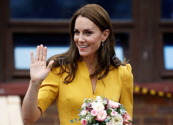 Integrante importante da família real britânica, Kate complementou o vestido amarelo brilhante, que faz referência ao verão, com saltos de camurça contrastantes e uma bolsa de mão azul-marinho