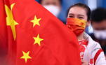 As chinesas também usaram as cores do país no principal acessório para evitar a disseminação do vírus. A atleta Liu Lingling usa a máscara e mostra a bandeira do país após vencer a prova no trampolim