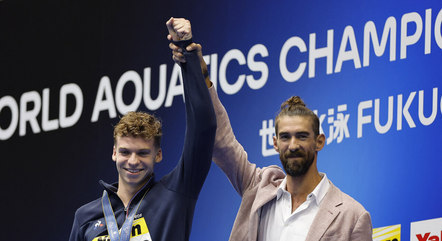 Michael Phelps ergueu o braço de Marchand, em comemoração
