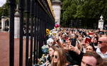 Fãs se espremem nas grades do palácio para fotografar e gravar a chegada de Charles, agora como rei, ao Palácio de Buckingham