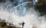 A Palestinian demonstrator runs away from tear gas canisters fired by Israeli forces during a protest against Jewish settlements, in Beit Dajan in the Israeli-occupied West Bank December 18, 2020. REUTERS/Mohamad Torokman
