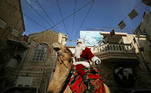 10 - Issa Kassissieh wears a Santa Claus costume as he rides a camel after handing out Christmas trees to people during the annual distribution of the trees organised by the Jerusalem municipality in Jerusalem's Old City December 22, 2020. REUTERS/Ammar Awad TPX IMAGES OF THE DAY