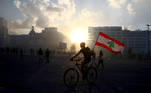 A demonstrator holding a Lebanese flag rides a bicycle during a protest following Tuesday's blast, in Beirut, Lebanon August 8, 2020. REUTERS/Hannah McKay