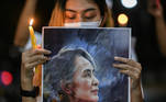 A person holds a candle and a picture of leader Aung San Suu Kyi as Myanmar citizens protest against the military coup in Myanmar outside United Nations venue in Bangkok, Thailand February 6, 2021. REUTERS/Chalinee Thirasupa