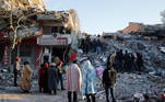 People stand in front of a collapsed building following an earthquake in Kahramanmaras, Turkey February 8, 2023. REUTERS/Dilara Senkaya
