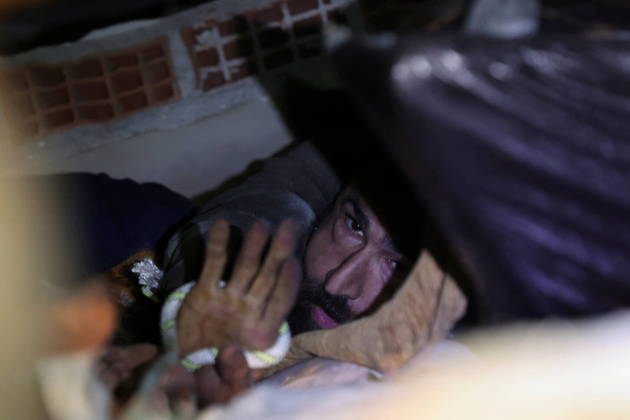 Abdulalim Muaini holds onto a rope as rescuers try to pull him out from under the rubble, in the aftermath of a deadly earthquake in Hatay, Turkey, February 8, 2023. REUTERS/Umit Bektas
