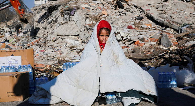 A girl sits near the site of a collapsed building following an earthquake in Kahramanmaras, Turkey February 8, 2023. REUTERS/Dilara Senkaya
