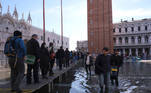 People walk on a catwalk at the flooded St. Mark's Square during seasonally high water in Venice, Italy November 5, 2021. REUTERS/Manuel Silvestri