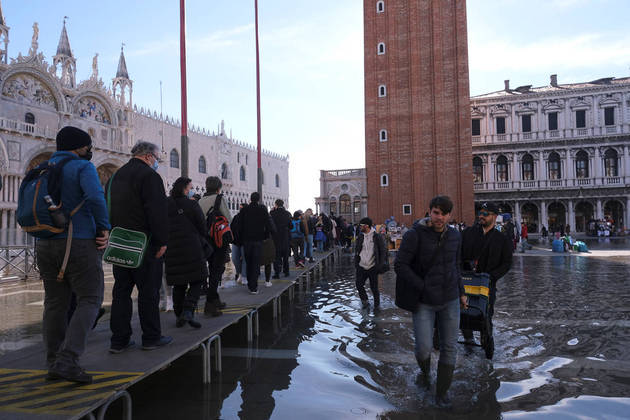 People walk on a catwalk at the flooded St. Mark's Square during seasonally high water in Venice, Italy November 5, 2021. REUTERS/Manuel Silvestri