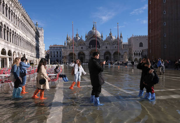 People walk through a flooded St. Mark's Square during seasonally high water in Venice, Italy November 5, 2021. REUTERS/Manuel Silvestri