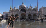 Women pose for a picture in a flooded St. Mark's Square during seasonally high water in Venice, Italy November 5, 2021. REUTERS/Manuel Silvestri