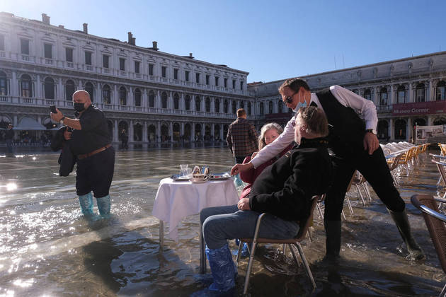 Visitors are served at a cafe in a flooded St. Mark's Square during seasonally high water in Venice, Italy November 5, 2021. REUTERS/Manuel Silvestri
