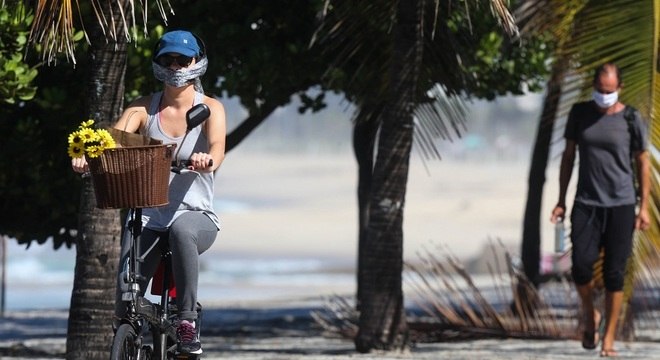 Ciclista e pedestre usam máscara em calçadão no Rio de Janeiro