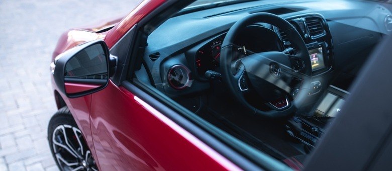 Interior com elementos na cor vermelha no painel, saídas de ar, volante e câmbio