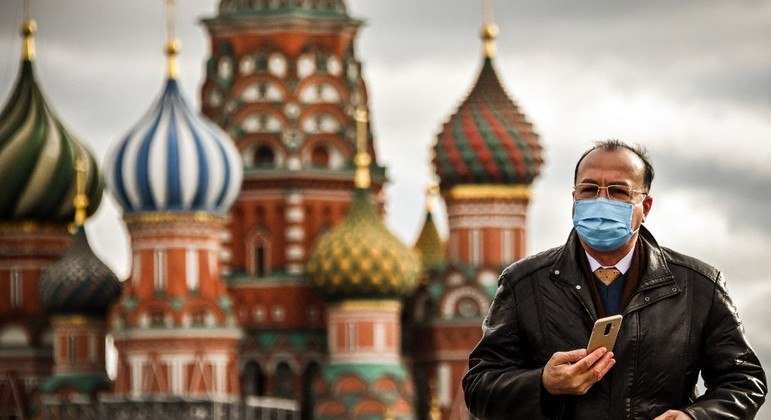 Homem usando máscara caminha ao longo da praça Vermelha, no centro de Moscou
