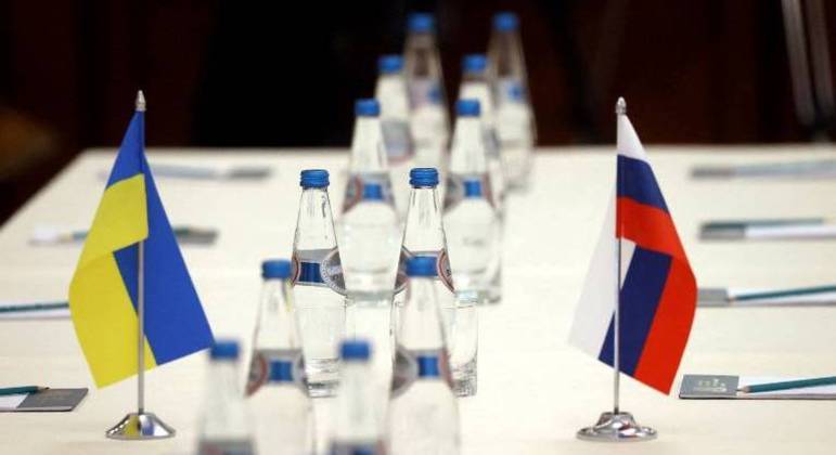 Bandeiras da Ucrânia e da Rússia são vistas em uma mesa antes das negociações 