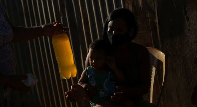 Moradora recebe um garrafa pet com detergente líquido, na Cidade Estrutural